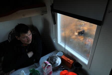 Sami reindeer herder Nils Mathis Sara, 60, takes a rest in a small cabin near Lake Iesjavri, as his dog Chappe waits outside, in the Finnmark Plateau, Norway, June 16, 2018. REUTERS/Stoyan Nenov/Files