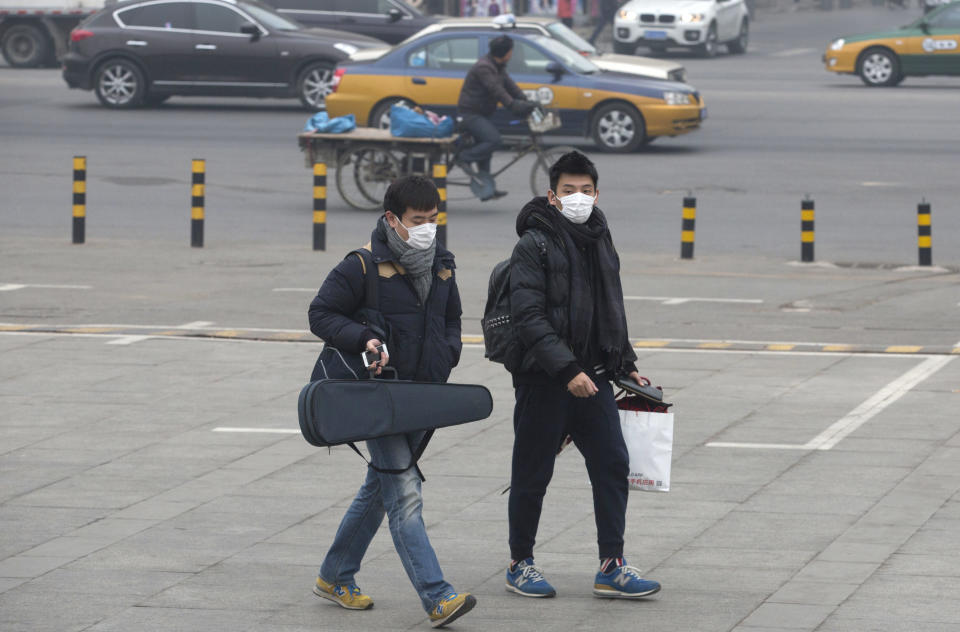 Men wearing masks walk near a road during a day of heavy pollution in Beijing, China, Sunday, Feb. 23, 2014. (AP Photo/Ng Han Guan)