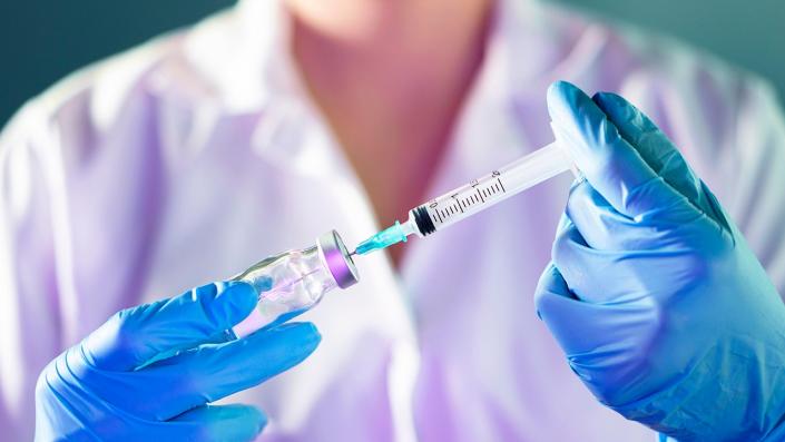 doctor in white lab coat prepares vaccine