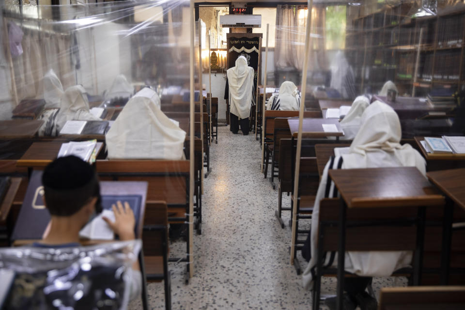 Ultra-Orthodox Jews pray in a synagogue separated by plastic shields, following new government measures to help stop the spread of the coronavirus, in Bnei Brak, Israel, Friday, Sept 18, 2020. Israel is set to go back into a three-week lockdown later Friday to try to contain a coronavirus outbreak that has steadily worsened for months as its government has been plagued by indecision and infighting. The closures coincide with the Jewish High Holidays, when people typically visit their families and gather for large prayer services. (AP Photo/Oded Balilty)