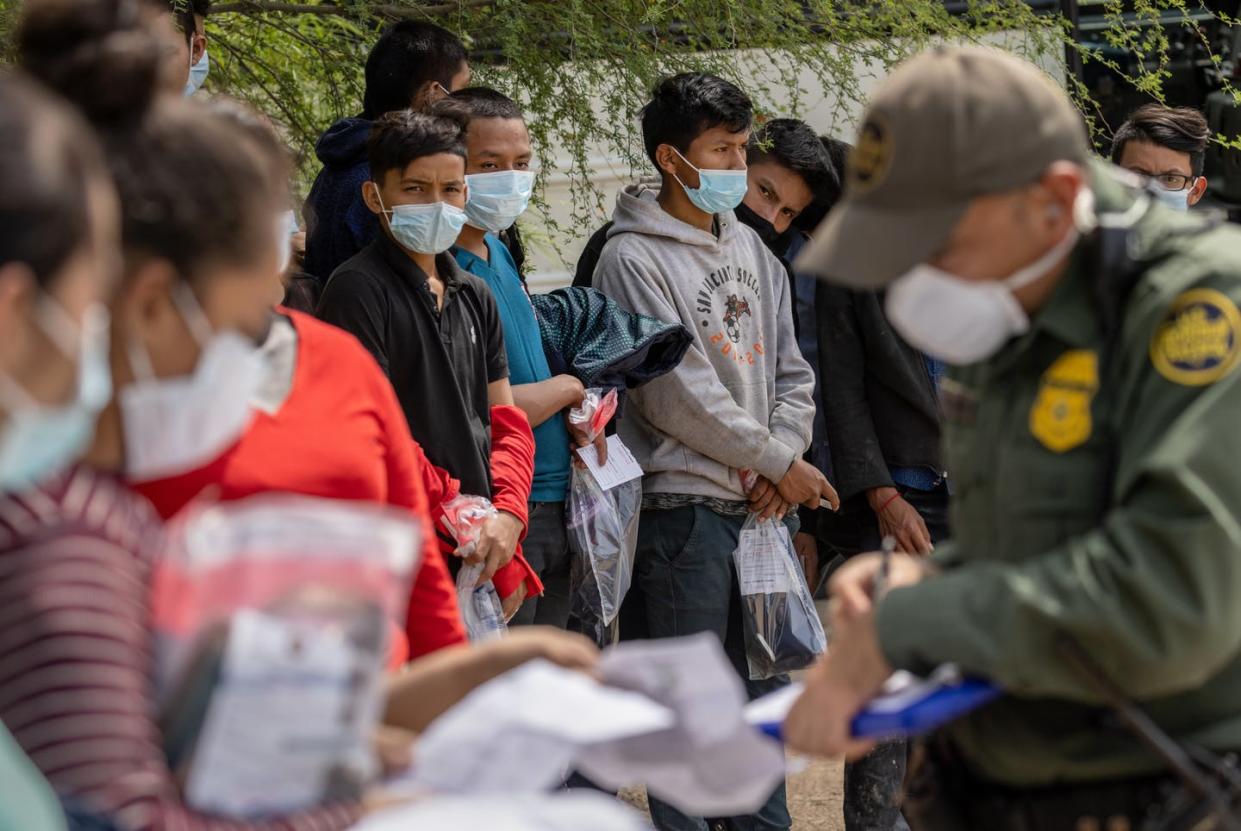 <span class="caption">Unaccompanied minors wait to see a Border Patrol agent after crossing the Rio Grande from Mexico into Texas on March 25, 2021.</span> <span class="attribution"><a class="link " href="https://www.gettyimages.com/detail/news-photo/border-patrol-agent-questions-families-as-a-group-of-news-photo/1309143366?adppopup=true" rel="nofollow noopener" target="_blank" data-ylk="slk:John Moore/Getty Images;elm:context_link;itc:0;sec:content-canvas">John Moore/Getty Images</a></span>