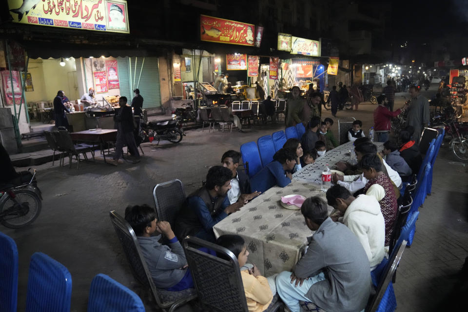 People wait to be served dinnert in the famous food street of Gawalmandi, an old area of Lahore, Pakistan, Sunday, Dec. 11, 2022. Gawalmandi is the city's neighborhood crammed with people, vehicles, animals, and food stalls. (AP Photo/K. M. Chaudary)