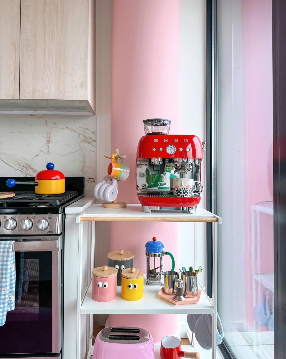 A shelf in a kitchen with colorful knick-knacks in front of a pink pillar.