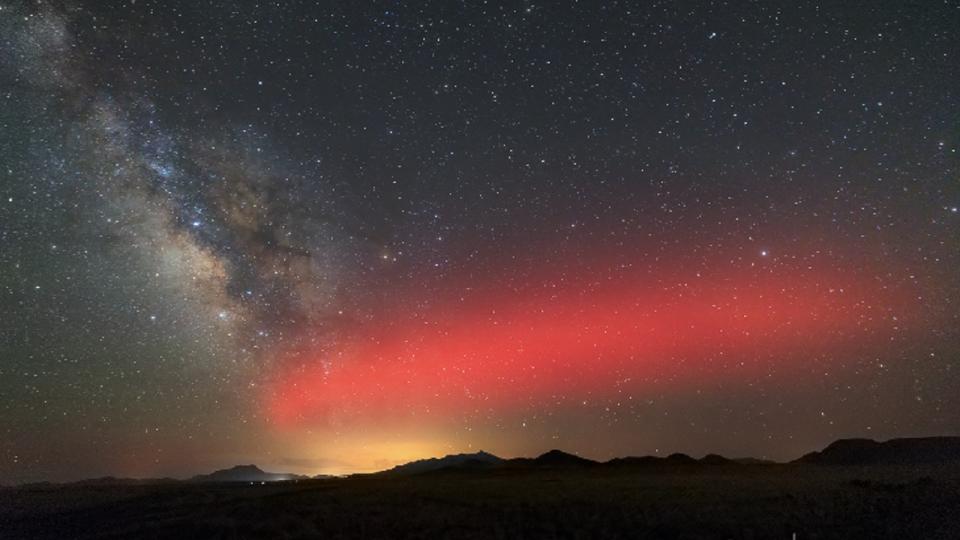 A large red streak shines across the night sky