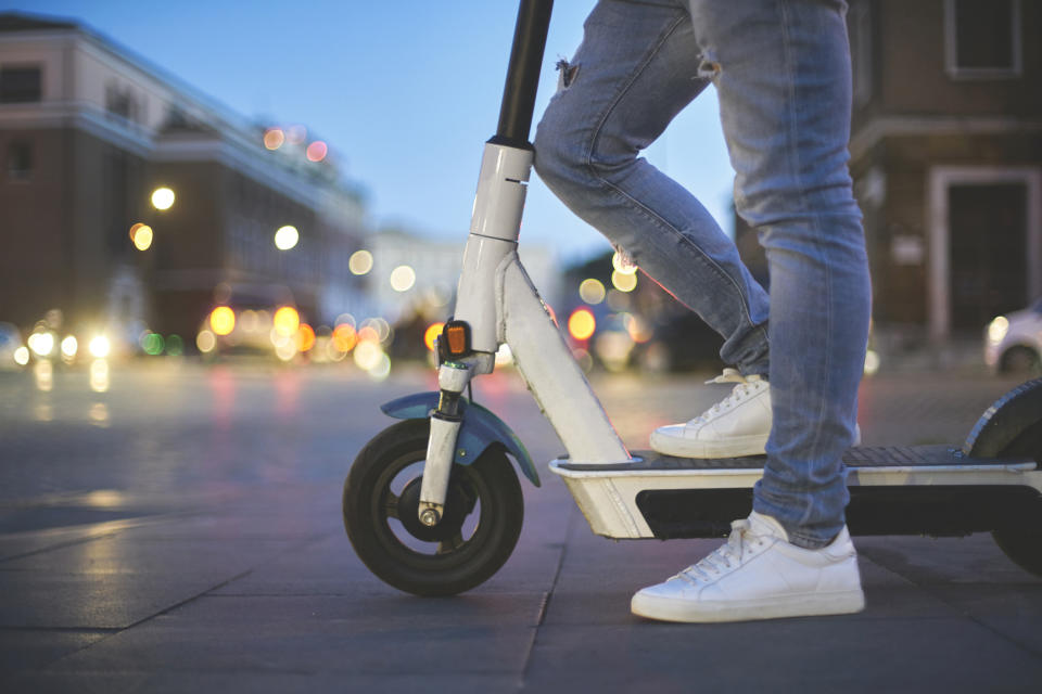 Person standing on an electric scooter on a city street at twilight