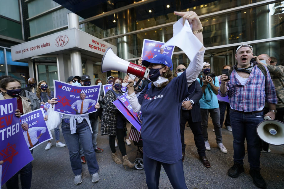 FILE - In this Oct. 15, 2020, file photo, protesters gather on the sidewalk outside the offices of New York Gov. Andrew Cuomo in New York. After shutdowns swept entire nations during the first surge of the coronavirus earlier this year, some countries and U.S. states are trying more targeted measures as cases rise again around the world. In New York City's borough of Brooklyn, Orthodox Jews have complained their communities are being singled out for criticism. (AP Photo/Kathy Willens)