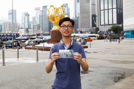 Kalok Leung, who was born four months after the Hong Kong's handover to Chinese rule in 1997, poses with his childhood photo which was taken at the same spot in 2002, at Golden Bauhinia Square in Hong Kong, China June 15, 2017. REUTERS/Tyrone Siu