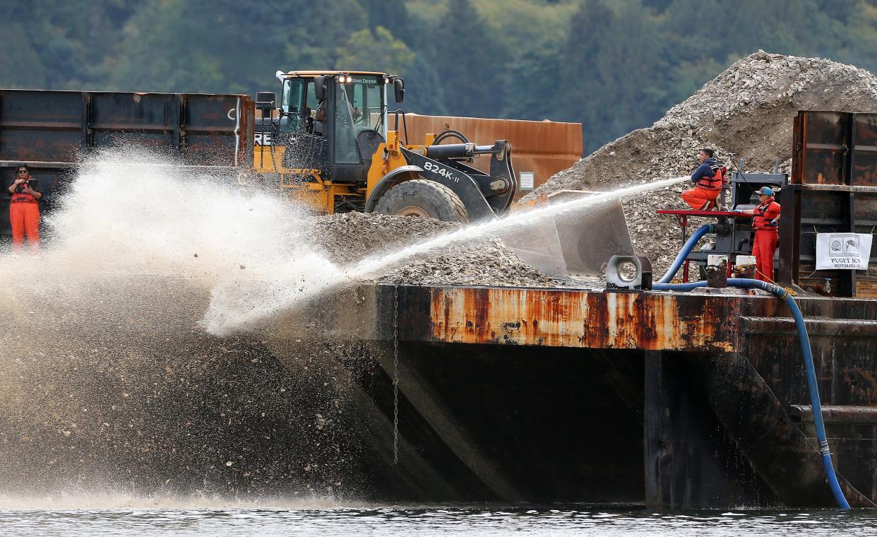 A high-powered hose of seawater is used to sluice Pacific oyster shells from the deck of a barge and into the water off the shore of Old Mill Park in Silverdale on Tuesday. Puget Sound Restoration Fund (PSRF) will spread 1,900 cubic yards of shells over up to 20 acres of tidelands, covering them in various densities as they work to restore habitat for the native Olympia oyster in Dyes Inlet.