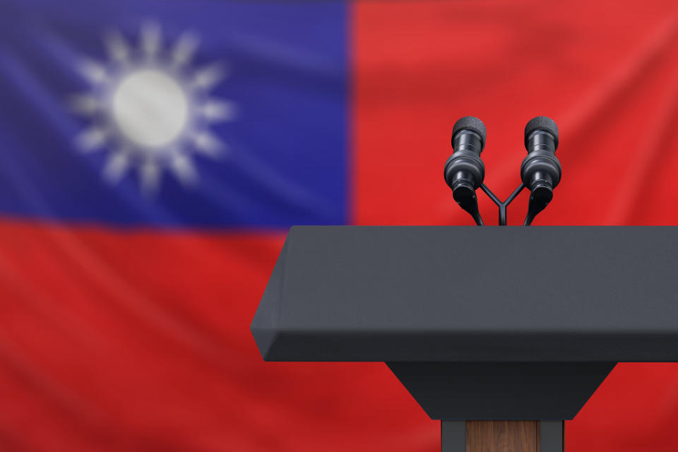 Podium lectern with two microphones and Taiwan flag in background