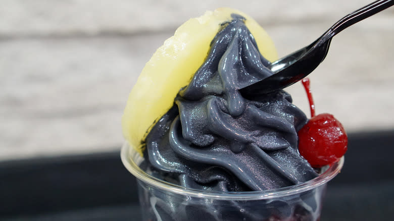 Cup of black soft serve with pineapple and cherry