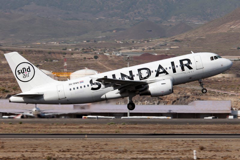 A plane lands on a sunny strip in a desert-mountain region in Spain.