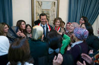 This photo taken on March 20, 2014 posted on the official Facebook page of the Syrian Presidency, shows first lady Asma Assad, right center background, and Syrian President Bashar Assad, left center background, talking with Syrian teachers, in Damascus, Syria. As Syrian army made gains on the battlefield, Assad's Britain-born wife has come out of seclusion, joining her husband's campaign to infuse confidence and optimism into the war-wrecked nation. Since January, Asma Assad has made several carefully scripted public appearances in the past months. (AP Photo/Syrian Presidency via Facebook)