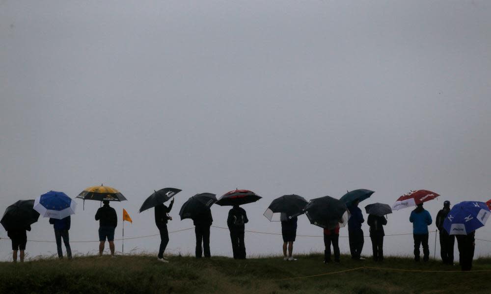 Spectators shelter under umbrellas due to heavy rain at the Open Championship at Royal Troon Golf Club, South Ayrshire, in July 2016