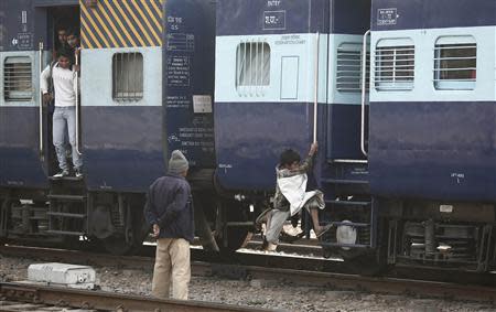 A ragpicker boy jumps onto a moving train in search of plastic bottles for reselling, at a railway station in New Delhi February 18, 2014. REUTERS/Adnan Abidi