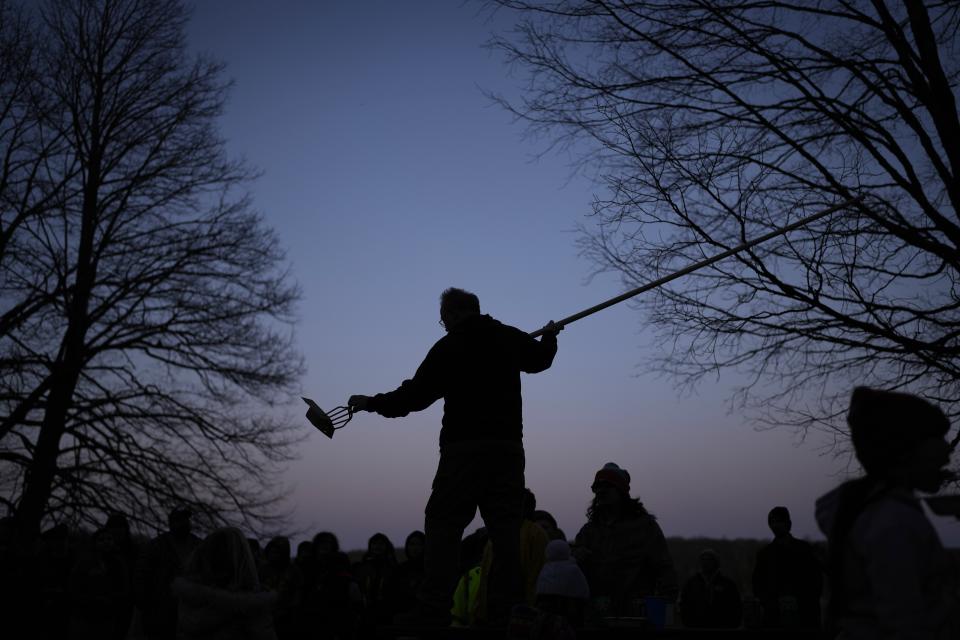 Mark Duffy, a member of the Red Cliff Band of Lake Superior Chippewa, stands on a picnic table while showing kids how to spearfish at a family and youth spearfishing event on Namekagon Lake, Friday, April 12, 2024, near Cable, Wis. (AP Photo/John Locher)