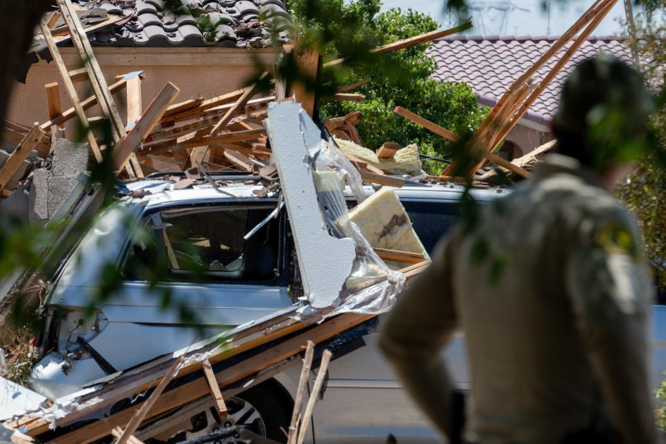 Debris lies on a vehicle at a destroyed house in the 14000 block of Adalane Court in Victorville on Wednesday, June 29, 2022. Authorities said an explosion occurred which injured a 40-year-old woman and damaged nearby houses.