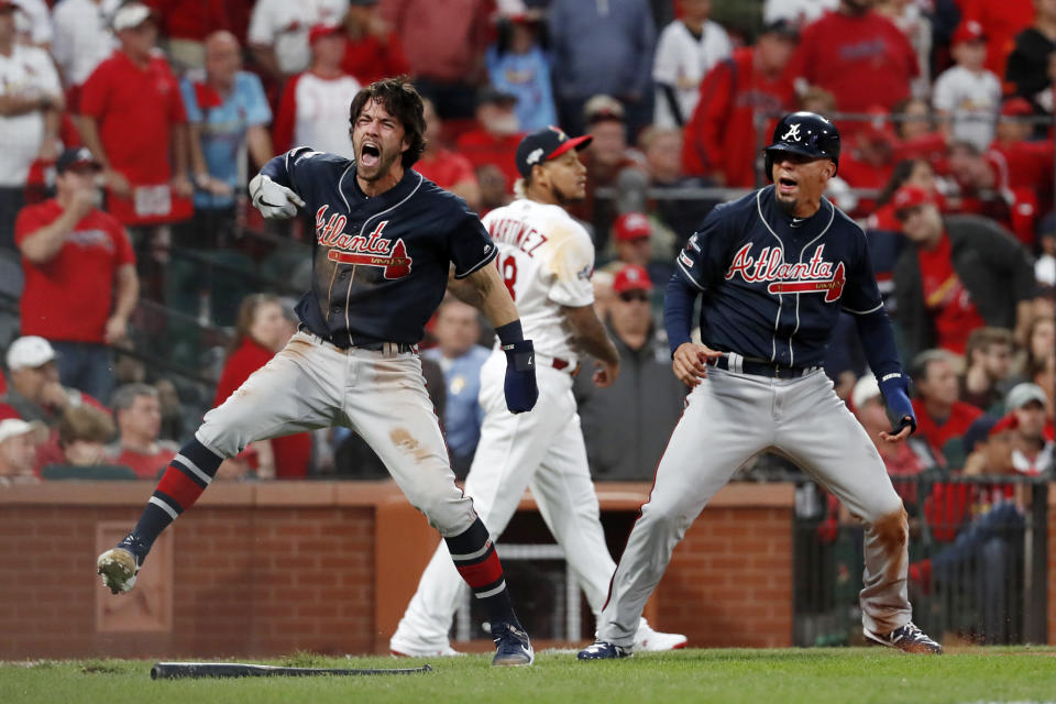 Atlanta Braves' Dansby Swanson, left, and Rafael Ortega, right, celebrate after scoring as St. Louis Cardinals relief pitcher Carlos Martinez (18) walks in the background during the ninth inning in Game 3 of a baseball National League Division Series on Sunday, Oct. 6, 2019, in St. Louis. (AP Photo/Jeff Roberson)