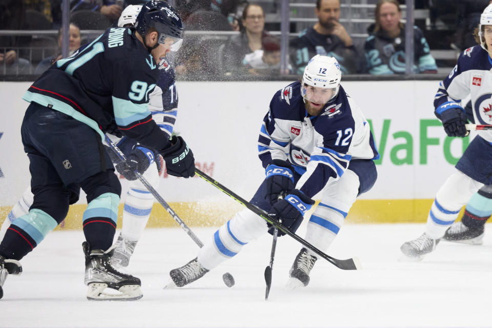 Seattle Kraken right wing Daniel Sprong battles for the puck with Winnipeg Jets center Jansen Harkins (12) during the first period of an NHL hockey game, Sunday, Dec. 18, 2022, in Seattle. (AP Photo/John Froschauer)