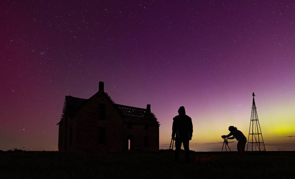 Photographers frame up an old abandoned house with the aurora borealis near the Marion and Chase County line on Friday night. The abandoned stone limestone house was built in 1878.