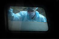 A man wearing personal protective equipment looks at the body of his relative who died of COVID-19 before cremation in Gauhati, India, Thursday, Sept. 10, 2020. India is now second in the world with the number of reported coronavirus infections with over 5.1 million cases, behind only the United States. Its death toll of only 83,000 in a country of 1.3 billion people, however, is raising questions about the way it counts fatalities from COVID-19. (AP Photo/Anupam Nath)