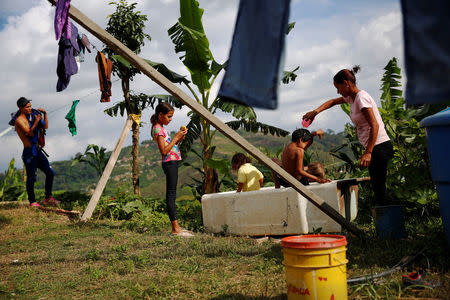 Lisibeht Martinez (R), 30, who was sterilized one year ago, plays with her children in a bathtub in the backyard of their house in Los Teques, Venezuela July 19, 2016. REUTERS/Carlos Garcia Rawlins