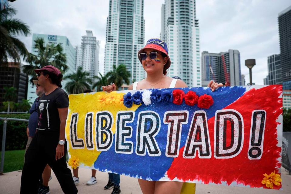 Carrying a banner bearing her country’s colors with the word ‘Freedom!’ written on it, Zarahy Carrera arrives at the rally at Bayfront Park