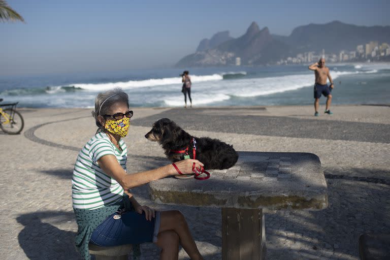 Lucía y su perro Jujuba se sientan en la playa de Arpoador, en medio de la nueva pandemia de coronavirus en Río de Janeiro, Brasil