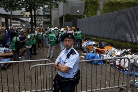 A policeman stands guard as workers from the Lands Department remove remaining tents outside government headquarters in Hong Kong, China June 24, 2015. REUTERS/Bobby Yip