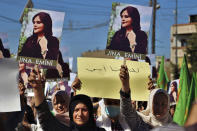 In this photo provided by Kurdish-run Hawar News Agency, Kurdish women hold up portraits of Iranian Mahsa Amini, during a protest condemning her death in Iran, in the city of Qamishli, northern Syria, Monday, Sept. 26, 2022. Protests have erupted across Iran in recent days after Amini, a 22-year-old woman, died while being held by the Iranian morality police for violating the country's strictly enforced Islamic dress code. (Hawar News Agency via AP via AP)
