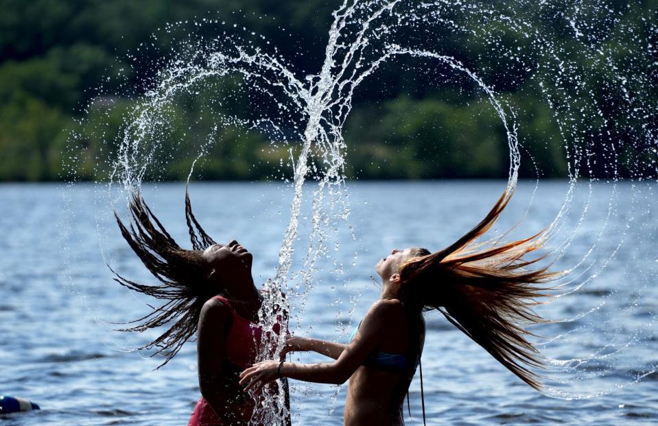 Tweens Gyanna Bey, 12, and Kaia Sherette, 13, of Providence, flip their water soaked hair up and back to form a water droplet heart for their aunt on shore while playing at Governor Notte Park beach in North Providence. Rhode Island is expecting a heat wave that is forecast through Sunday.