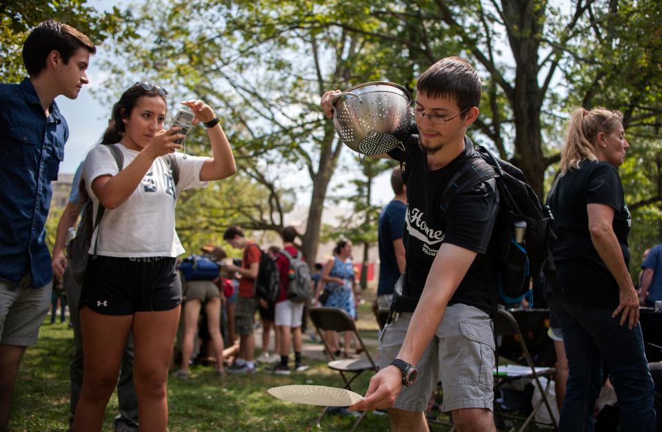 An Indiana University senior studying chemistry, right, projects the eclipse onto a paper plate using a colander during the solar eclipse in Bloomington, Indiana on Aug. 21, 2017.