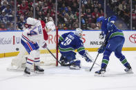 Montreal Canadiens' Montreal Canadiens' Nick Suzuki (14) misses the puck as he stands at the open net behind Vancouver Canucks goalie Casey DeSmith (29), while Noah Juulsen, right, watches during the second period of an NHL hockey game Thursday, March 21, 2024, in Vancouver, British Columbia. (Darryl Dyck/The Canadian Press via AP)
