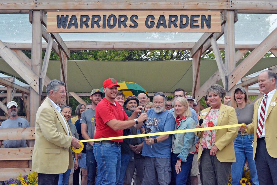 Billy Froeschner with Columbia Center for Urban Agriculture and Mark Stevenson prepare to cut the ribbon Wednesday on the handicapped-accessible Warriors Garden at the Mark and Carol Stevenson Veterans Urban Farm.