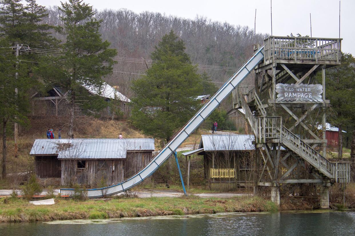 Large abandoned waterslide, Dogpatch USA, Newton County, Arkansas, lake in the foreground, abandoned buildings surround it, evergreen trees and bare trees in the background on a winter day