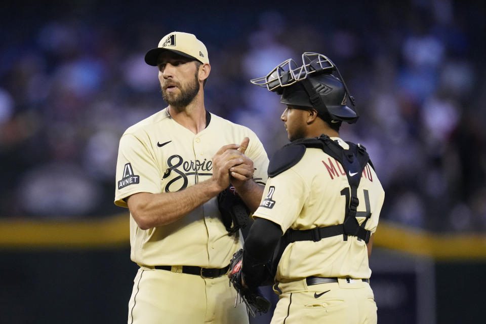 Arizona Diamondbacks starting pitcher Madison Bumgarner, left, gets a visit from catcher Gabriel Moreno, right, during the first inning of a baseball game against the Los Angeles Dodgers, Friday, April 7, 2023, in Phoenix. (AP Photo/Ross D. Franklin)