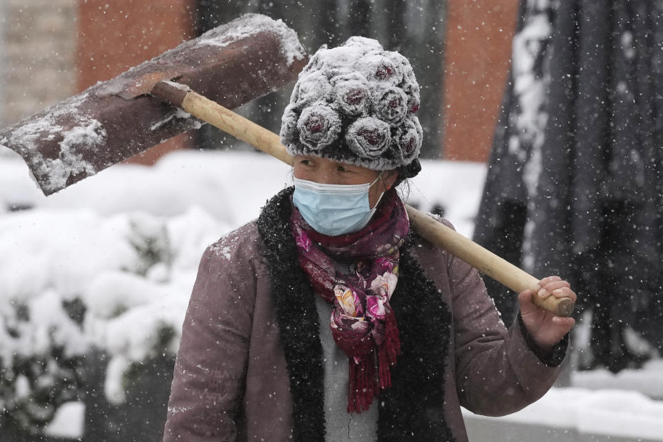 A worker walks with a shovel as fresh snow falls in Beijing, China, Sunday, Nov. 7, 2021. An early-season snowstorm has blanketed much of northern China including the capital Beijing, prompting road closures and flight cancellations. (AP Photo/Ng Han Guan)