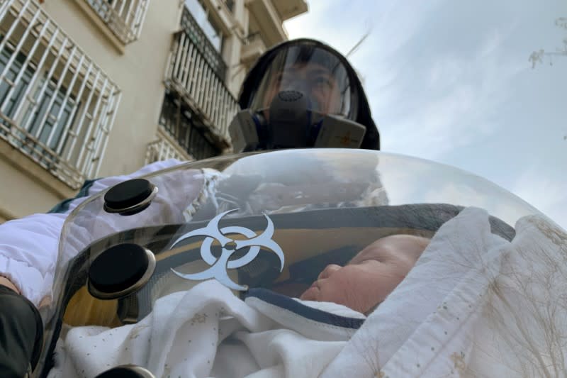 Cao Junjie poses for a picture with his two-month old baby inside a safety pod he created to protect his baby from the coronavirus disease in Shanghai