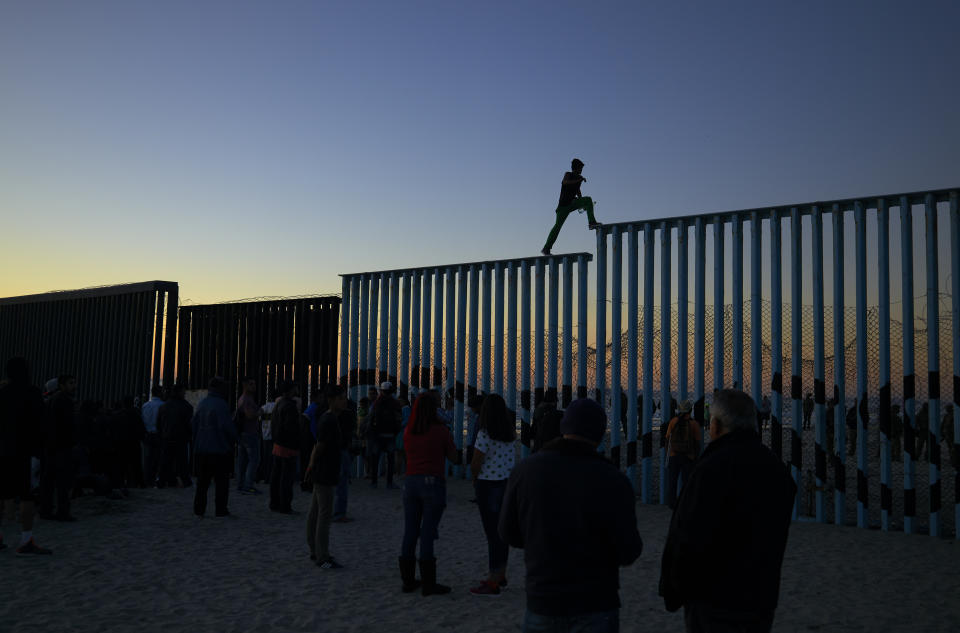 In this Nov. 14, 2018 picture, a man from Honduras walks along the top of the border structure separating Mexico and the United States, in Tijuana, Mexico. With about 3,000 Central American migrants having reached the Mexican border across from California and thousands more anticipated, the city of Tijuana continues to prepare for an influx that will last at least six months and may have no end in sight. (AP Photo/Gregory Bull)