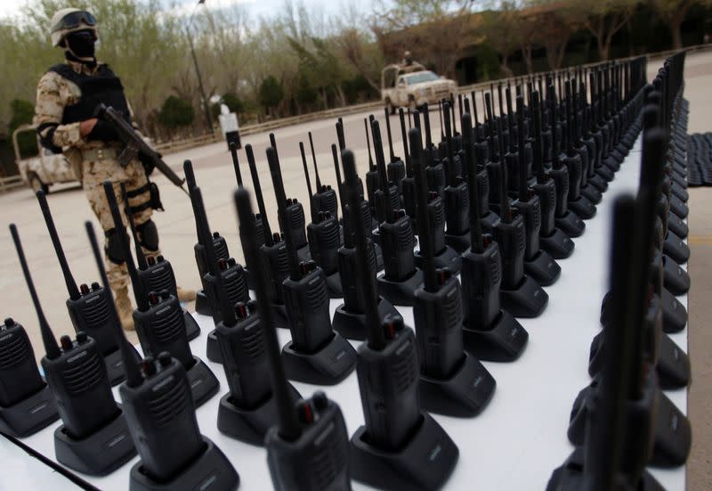 FILE PHOTO: An armed soldier stands guard next to communication radios displayed to the media at a military base in Ciudad Juarez