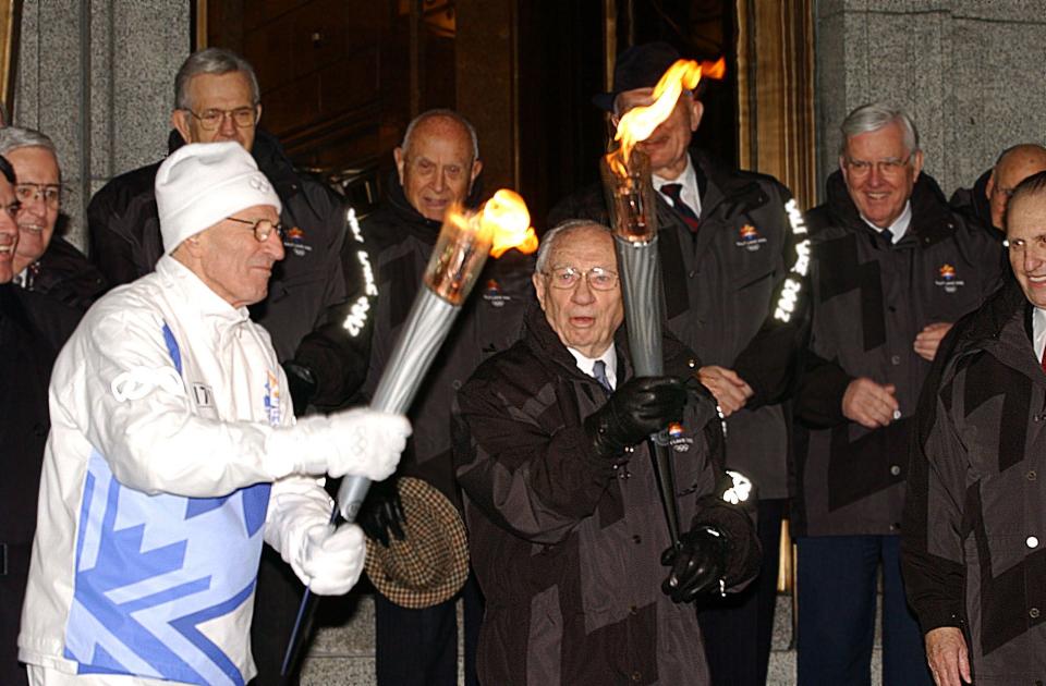 President Gordon B. Hinckley, president of The Church of Jesus Christ of Latter-day Saints, lights an Olympic torch being held by Elder Neal A. Maxwell, a member of the Quorum of the Twelve Apostles, at the Church Administration Building in Salt Lake City on Thursday Feb. 7, 2002. | Scott G Winterton, Deseret News