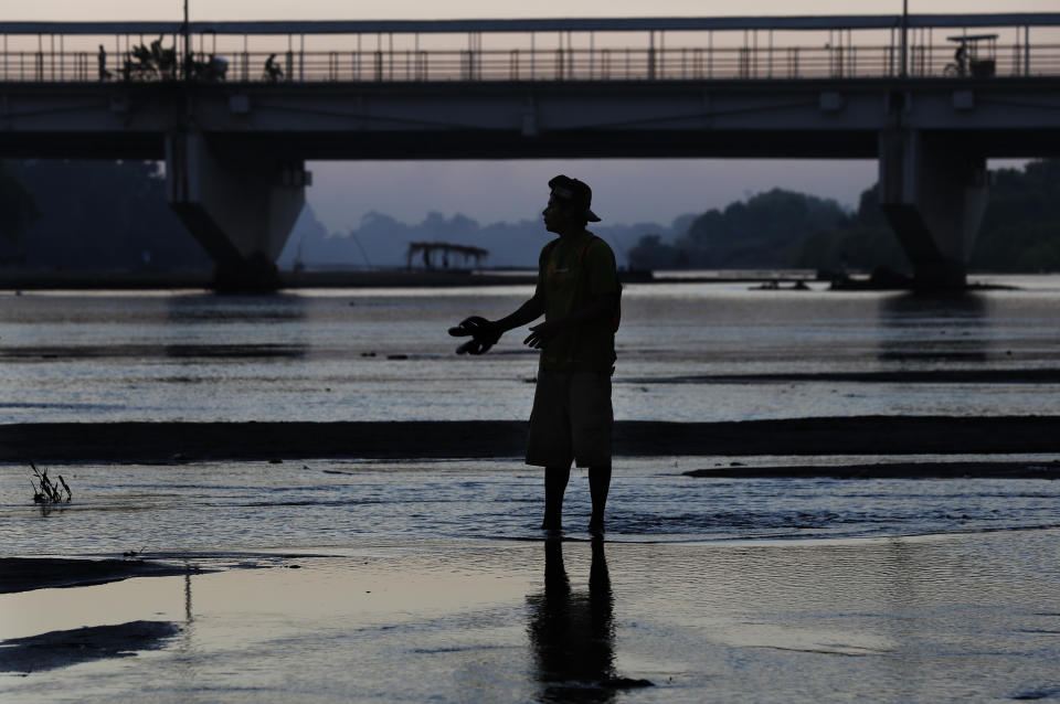 A migrant stands in the Suchiate River as he crosses from Guatemala to Mexico, near Ciudad Hidalgo, Chiapas state, Mexico, early Friday, Jan. 17, 2020. United States officials are crediting tough measures taken over the past year and cooperation from regional governments for sharply reducing the number of Central American migrants who responded to a call for a new caravan. (AP Photo/Marco Ugarte)