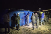 Smugglers lift onto a vehicle a fishing boat intended to carry migrants to the Canary Islands, in a remote desert out of the town of Dakhla in Morocco-administered Western Sahara, Tuesday, Dec. 22, 2020. The peninsula city of Dakhla boasts a thriving fishing port, and kitesurfing enthusiasts flock to its waters. But in recent months, its beaches have become a hot spot of the moment for smuggling networks eyeing the Canaries, 500 kilometers (300 miles) north.(AP Photo/Mosa'ab Elshamy)