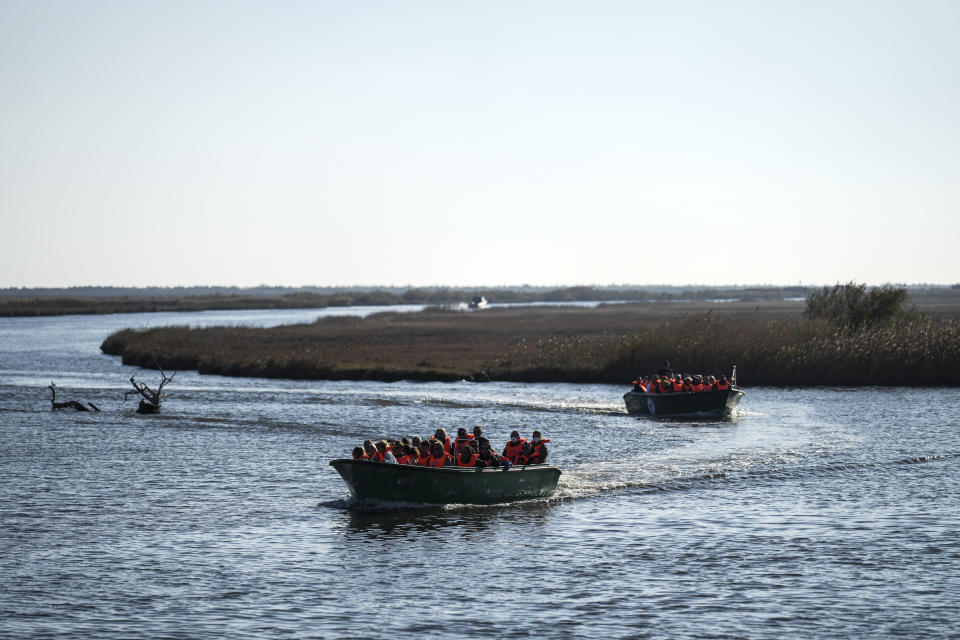 Tourist take part on a boat trip along the Evros River that forms a natural border between Greece and Turkey, on Sunday, Oct. 30, 2022. Greece is planning a major extension of a steel wall along its border with Turkey in 2023, a move that is being applauded by residents in the border area as well as voters more broadly. (AP Photo/Petros Giannakouris)