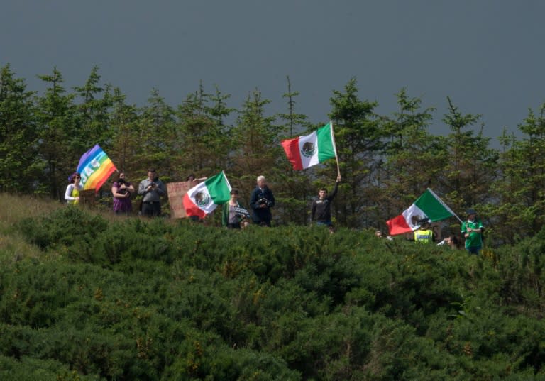 A group of protesters wave Mexican flags on the hillside above the Trump International Golf Links minutes before Donald Trump's arrival at the course, north of Aberdeen on the East coast of Scotland, on June 25, 2016