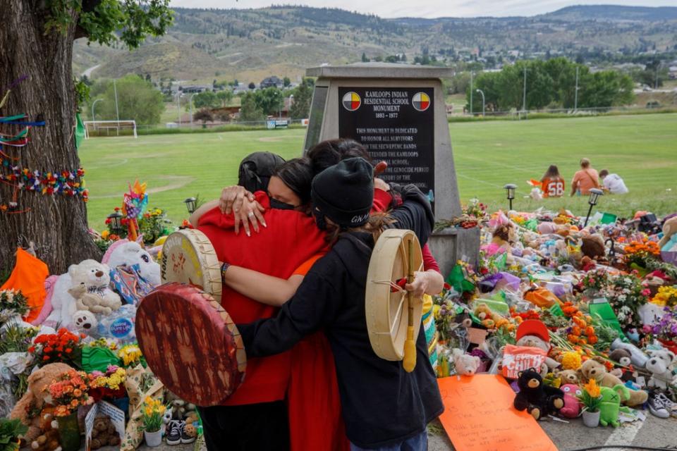 People from Mosakahiken Cree Nation hug in front of a makeshift memorial at the former Kamloops Indian Residential School in Canada, where the remains of 215 children were discovered earlier this year (AFP via Getty Images)