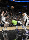 Minnesota Timberwolves' Patrick Beverley (22) falls as he attempts to shoot against San Antonio Spurs' Jakob Poeltl, left, and Tre Jones during the first half of an NBA basketball game on Monday, March 14, 2022, in San Antonio. (AP Photo/Darren Abate)