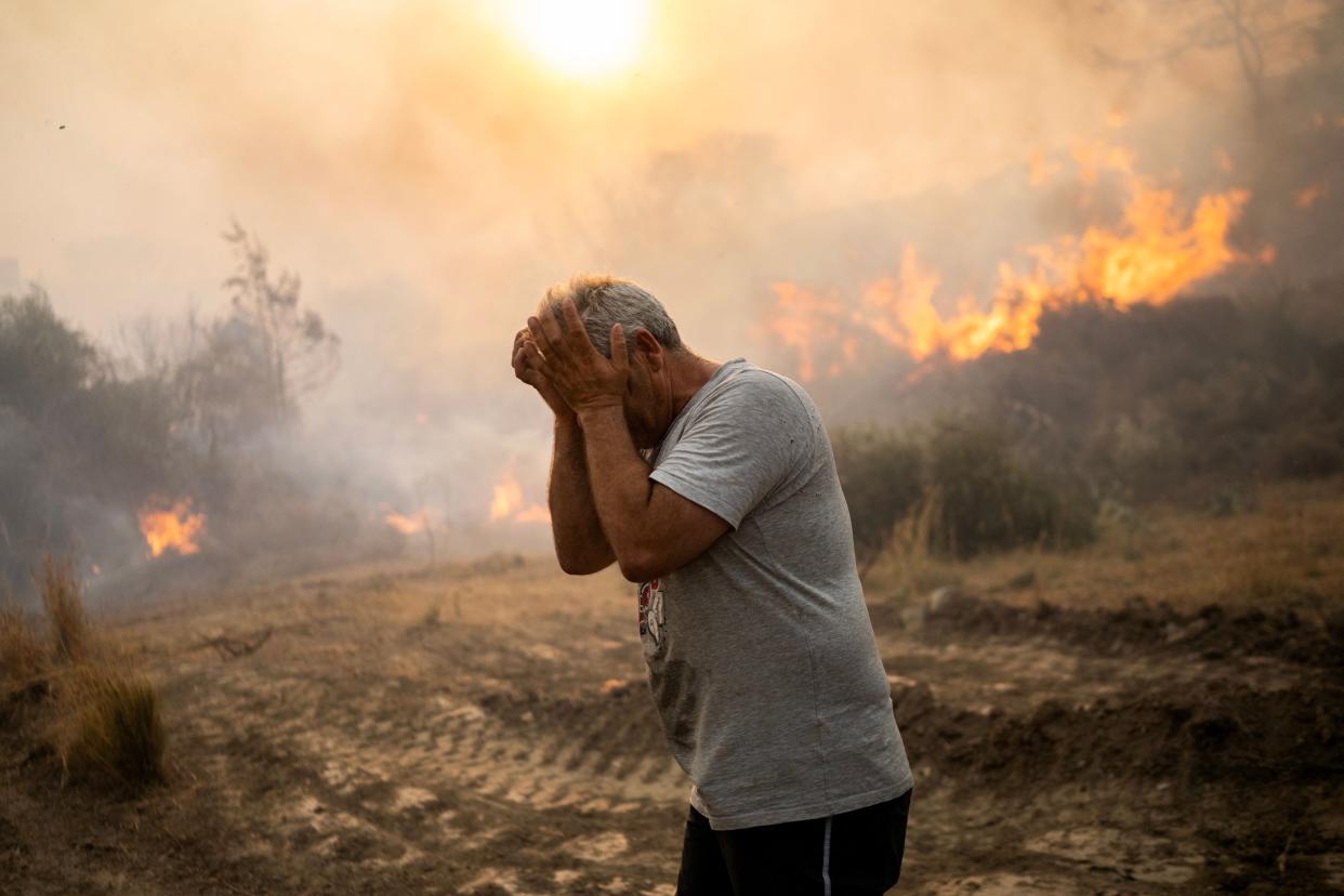 A man reacts as a fire burns in a village on the Greek Aegean island of Rhodes (AFP via Getty Images)