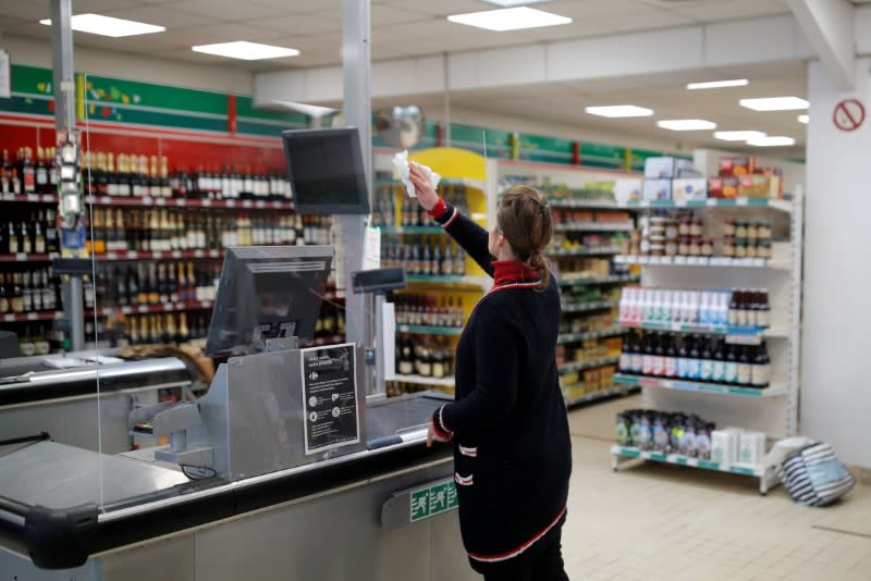 A cashier washes a glass protection at a minimarket in Saint-Jacut-de-la-Mer in Brittany