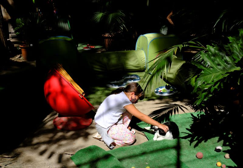 Una niña acaricia a un gato en el refugio El Jardinet dels Gats de Barcelona