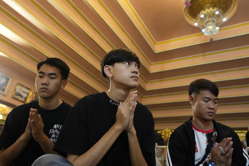 From left, Natthawut Thakhamsong, Prachak Sutham, and soccer coach Ekkapol Chanthawong, members of the Wild Boars soccer team who were rescued from a 2018 flooded cave, pray during a funeral ceremony for Duangphet Phromthep, at Wat Phra That Doi Wao temple in Chiang Rai province, Thailand, Sunday, March 5, 2023. The cremated ashes of Duangphet arrived in the far northern Thai province of Chiang Rai on Saturday where final Buddhist rites for his funeral will be held over the next few days following his death in the U.K. (AP Photo/Sakchai Lalit)